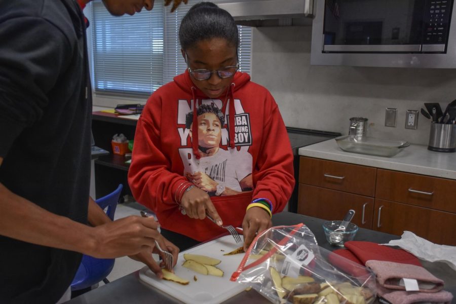 Kennedi Brooks (10) and Alex Anderson (10) are poking holes in the potatoes with forks so it cooks properly.